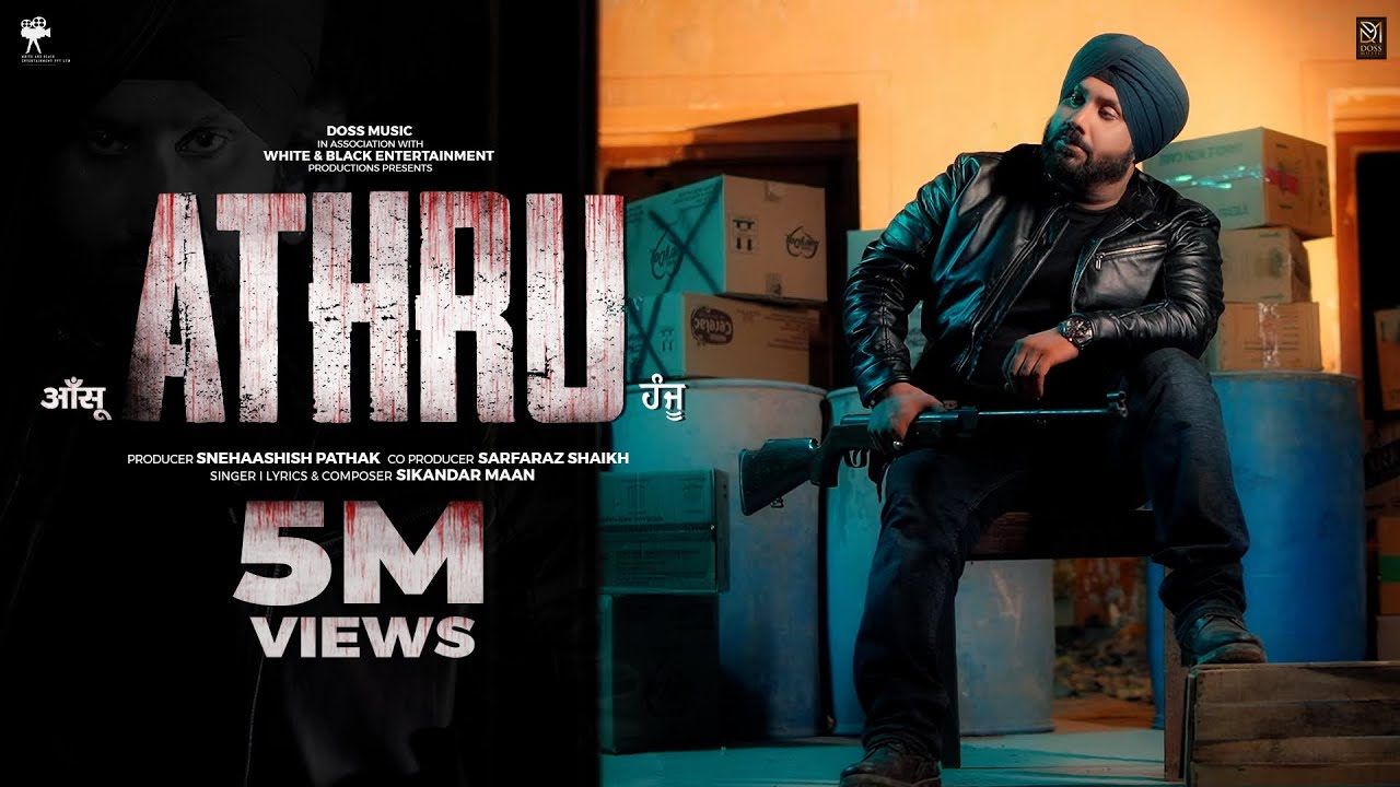 ATHRU (2025) artwork by Doss Music: Sikandar Maan in a black leather jacket and teal turban, seated among stacked boxes, beside the ATHRU title, the producer credits and a “5M views” badge.